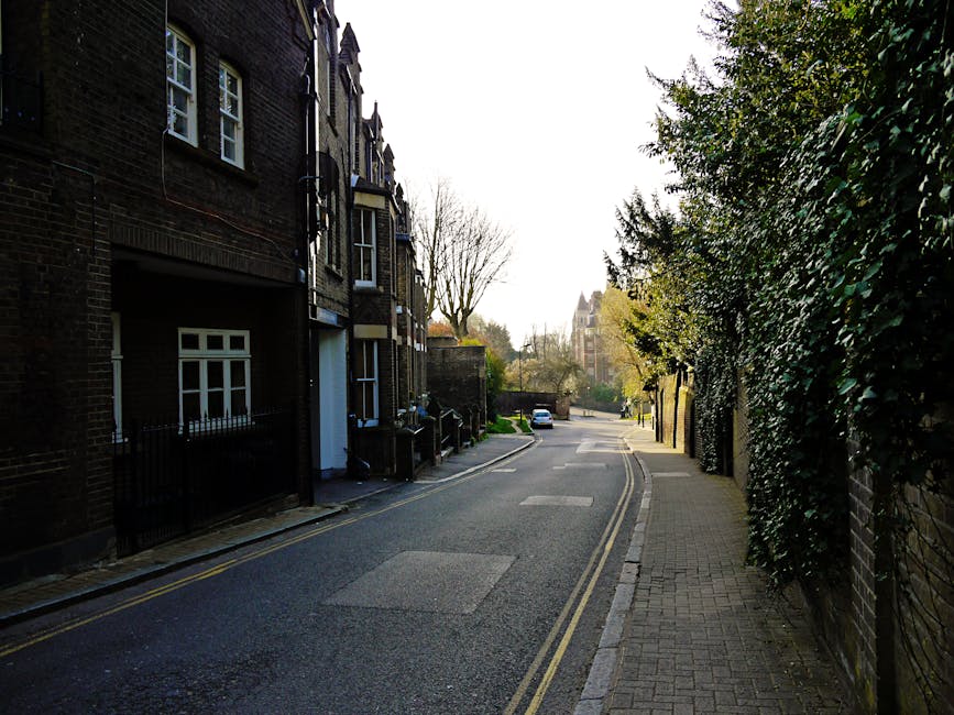 Close-up view of a street sign mounted on a red brick wall indicating 'Lower Terrace NW3' in Hampstead, with the sign featuring white text on a dark background and slightly weathered edges. In the bac